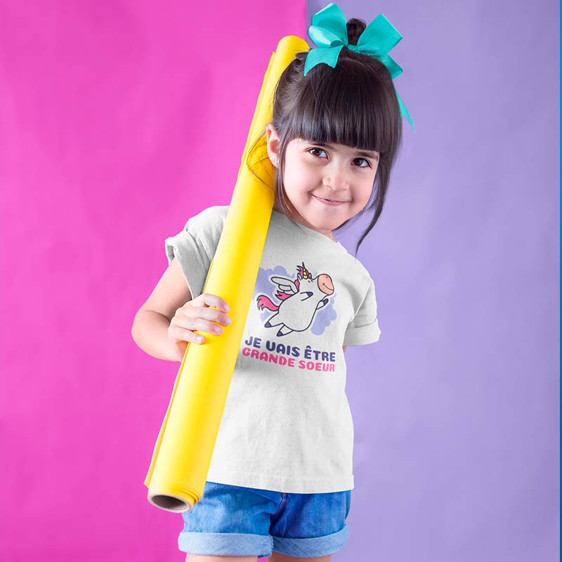 fille avec un t shirt blanc je vais être grande soeur et noeud dans les cheveux